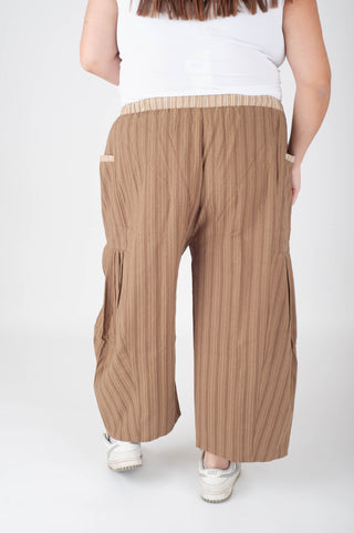 Person wearing beige wide-leg pants on a white background
