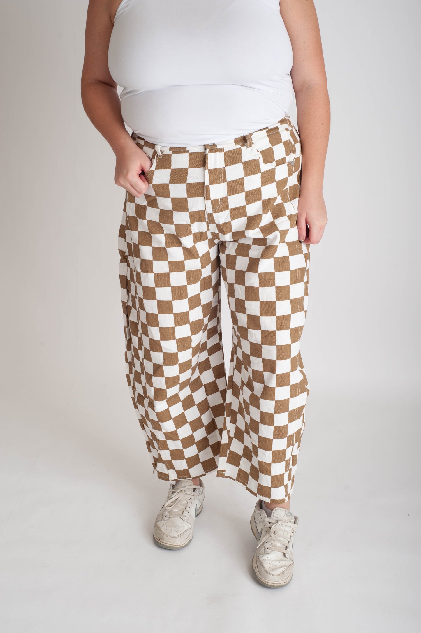 Person wearing brown and white checkered pants on a plain background