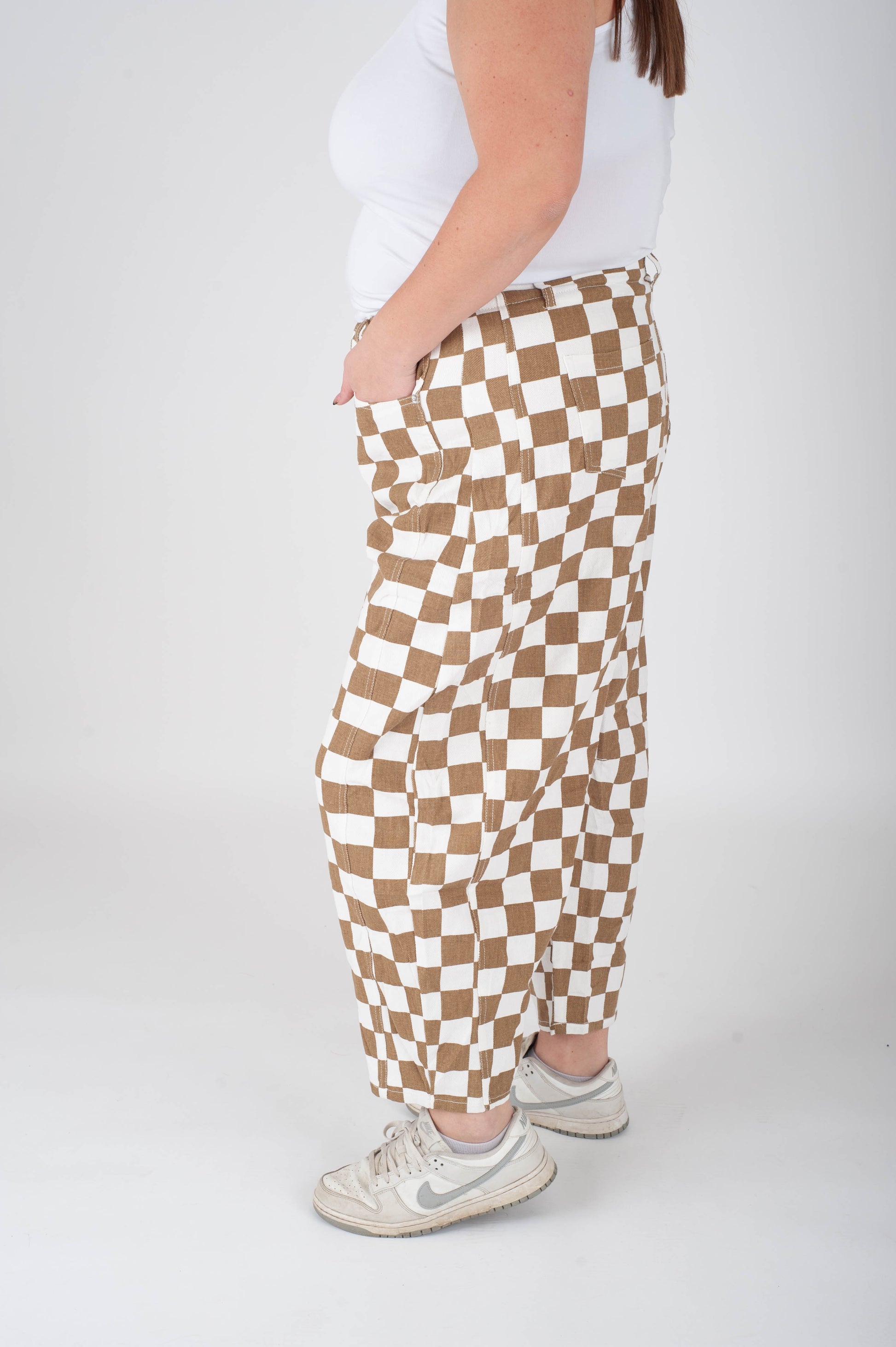 Person wearing brown and white checkered pants on a white background