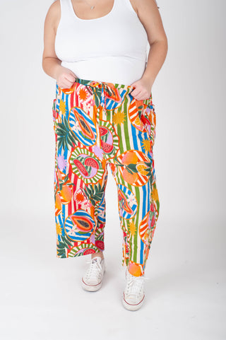 Person wearing colorful tropical print pants and white sneakers on a white background
