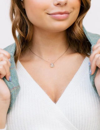 Close-up of a woman wearing a necklace with a heart pendant.