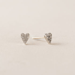 Heart-shaped earrings with embedded stones on a light beige background