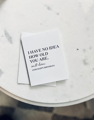 White card with humorous birthday message on a marble surface