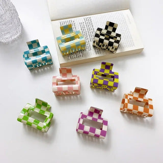 Set of colorful checkered hair clips on a white surface with a magazine in the background.