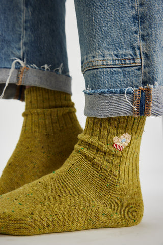 Yellow socks with a floral design on the cuff worn with blue jeans.