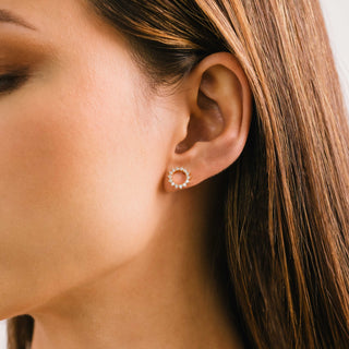 a person wearing a gold circular stud earring with cz diamond studs