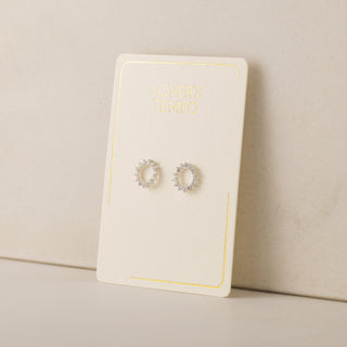 Pair of silver hoop earrings on a white card with a beige background