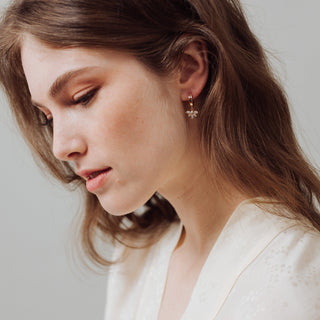Close-up of a woman wearing a delicate earring with a neutral background
