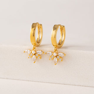 Gold hoop earrings with butterfly-shaped charms on a light background