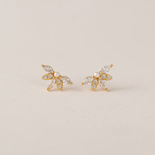 Gold earrings with gemstones on a light beige background