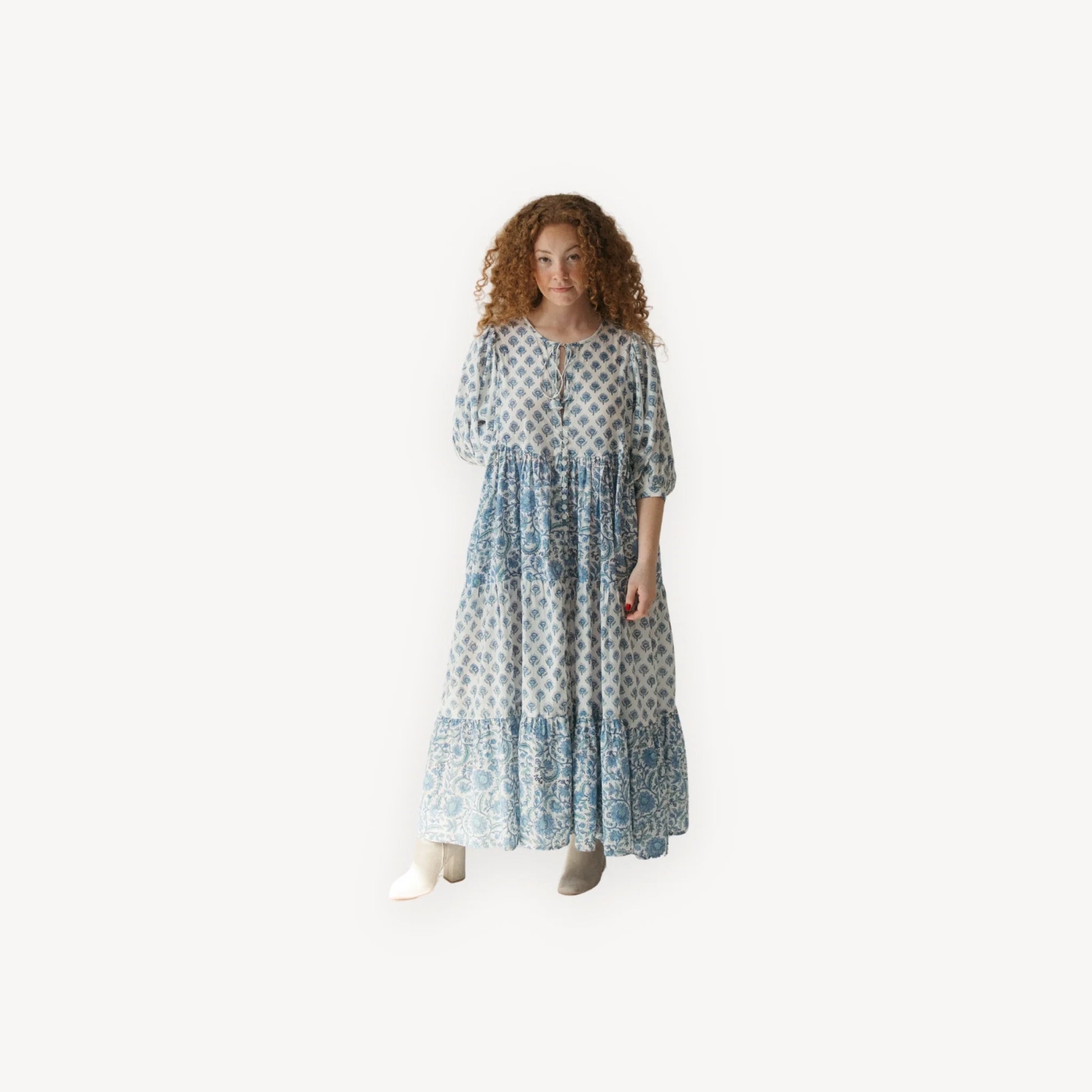 Woman wearing a long, patterned dress on a white background