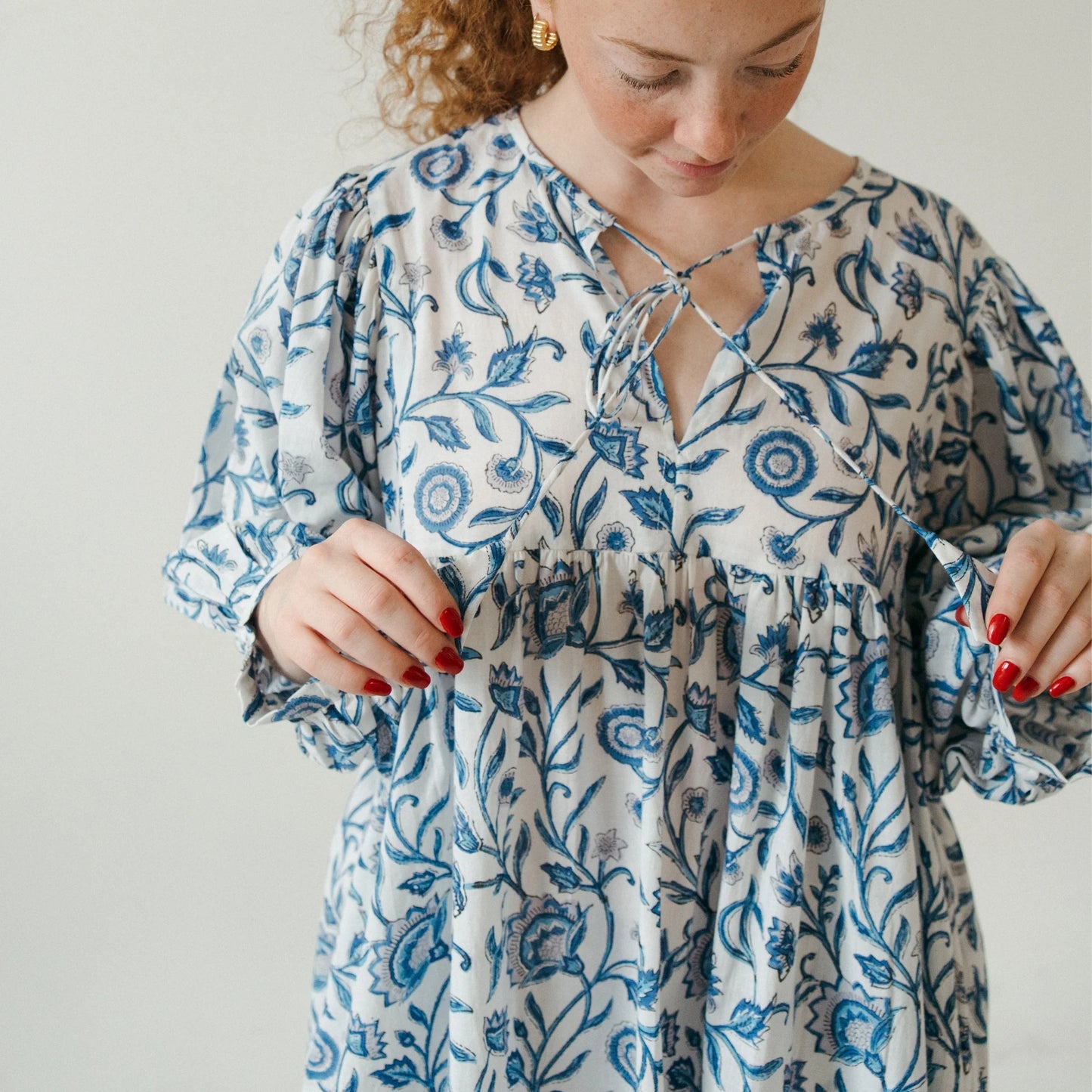 Woman wearing a blue floral dress against a plain background