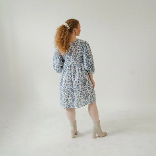 Woman wearing a blue floral dress standing against a white background
