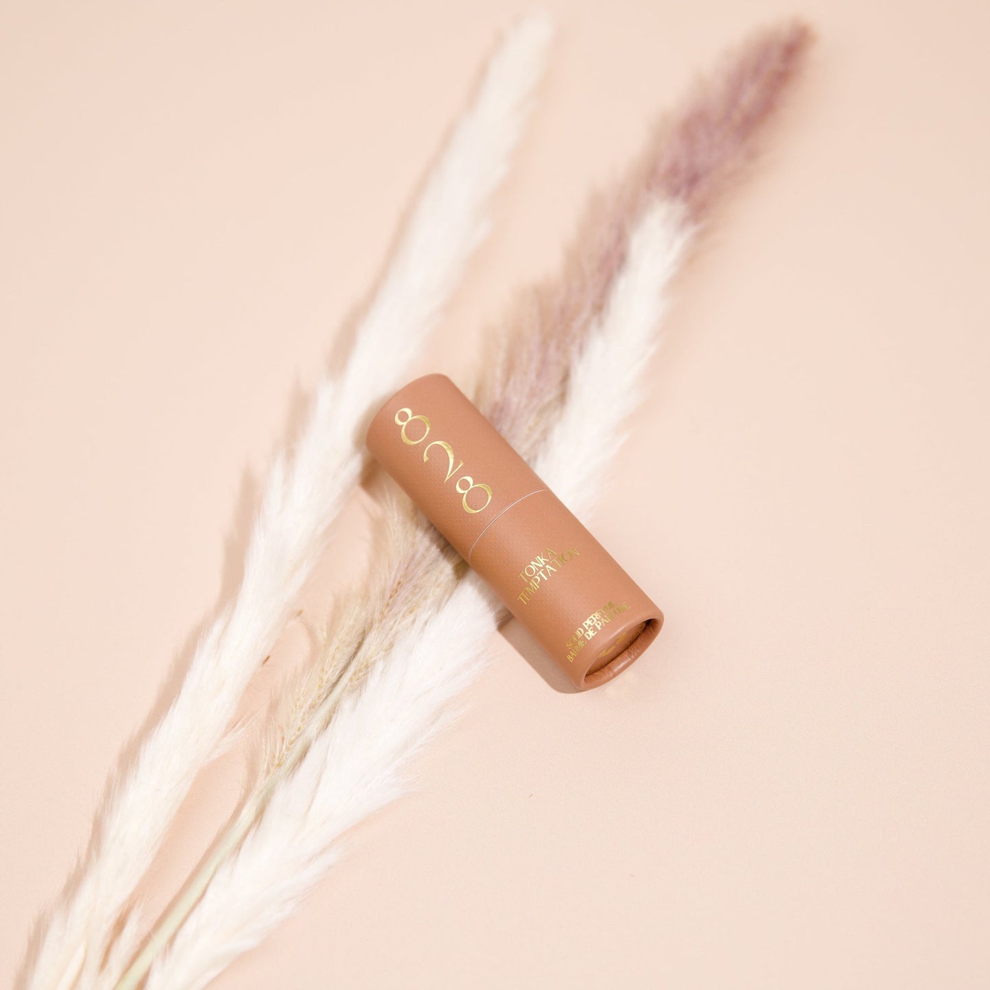 Cosmetic perfume stick with brand logo on a soft beige background