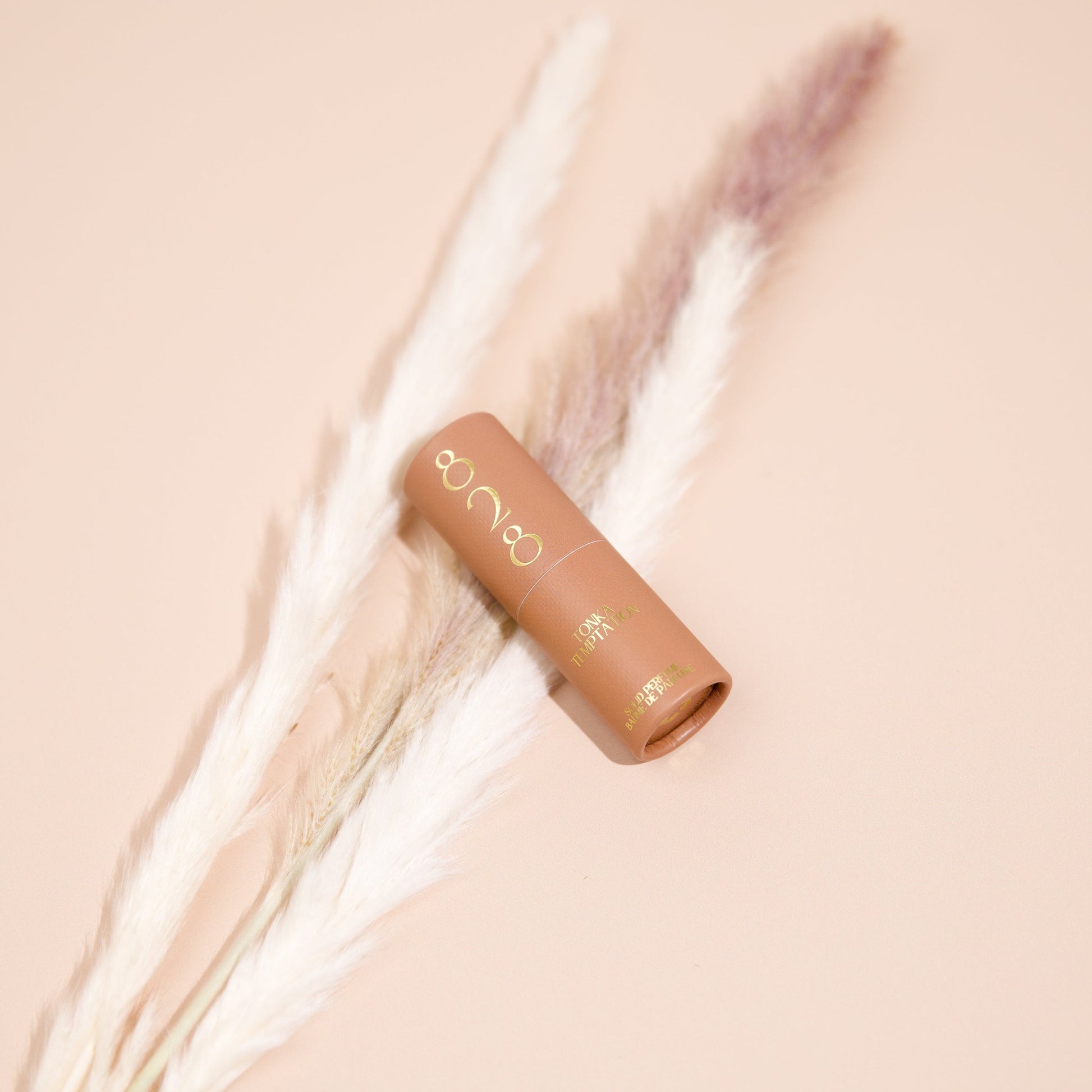 Cosmetic perfume stick with brand logo on a soft beige background