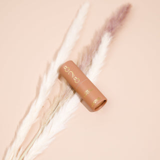 Cosmetic perfume stick with brand logo on a soft beige background