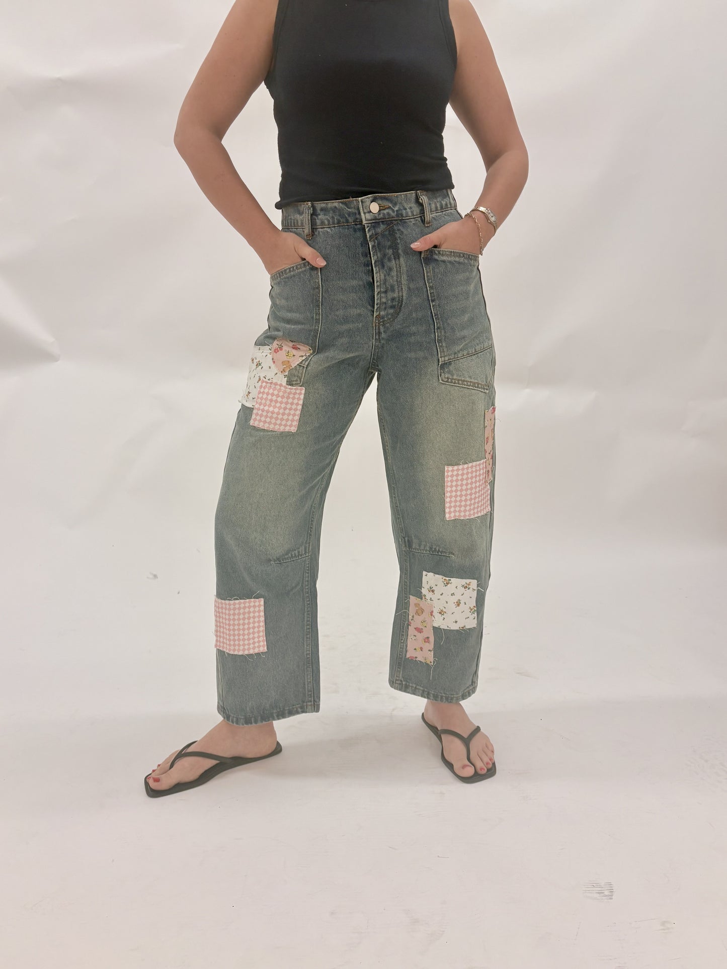 Person wearing patchwork jeans on a white background