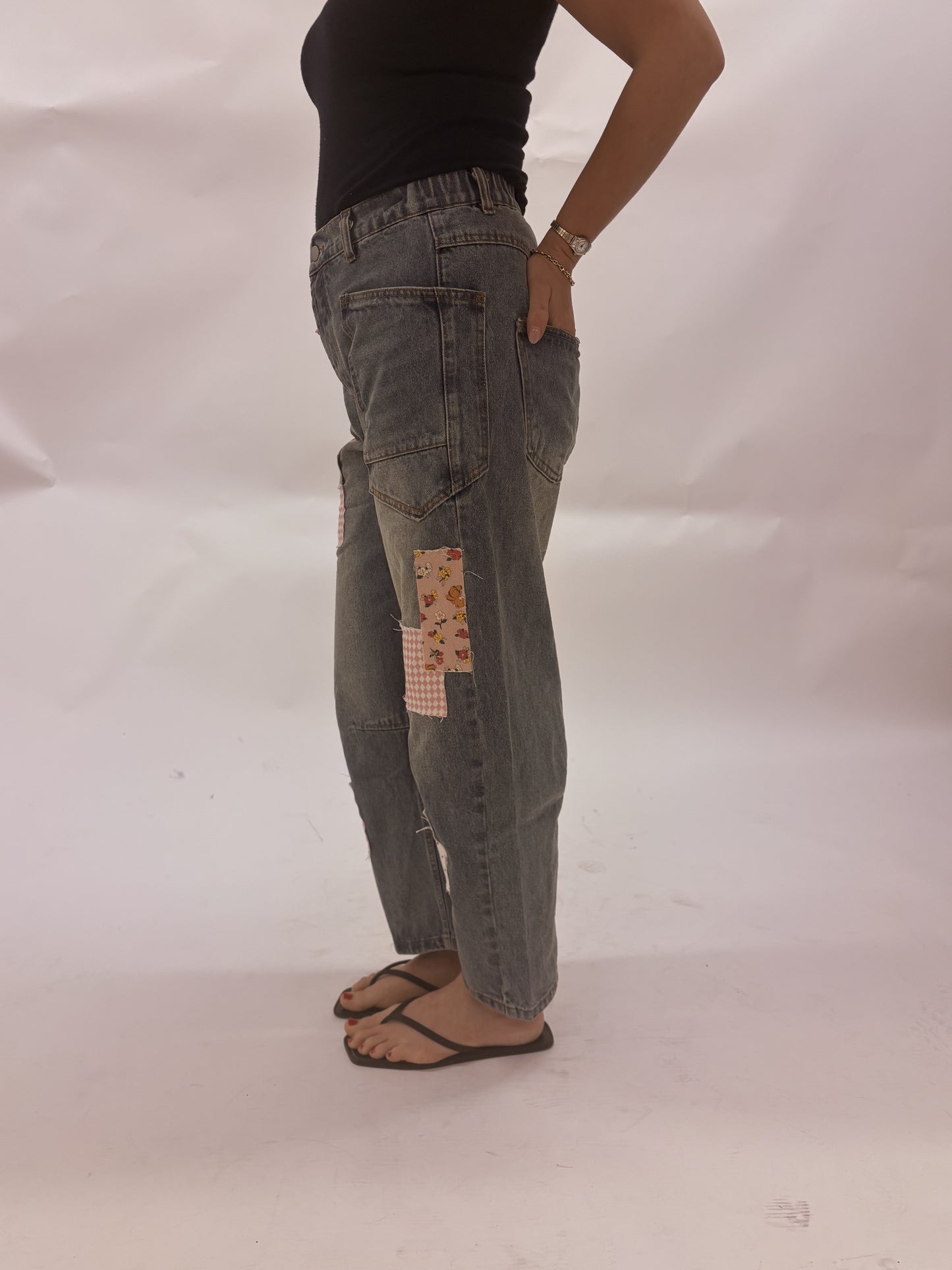 Person wearing patchwork jeans on a plain background