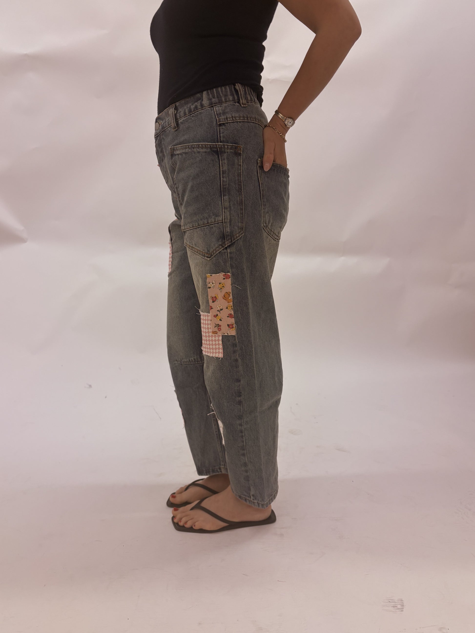 Person wearing patchwork jeans on a plain background