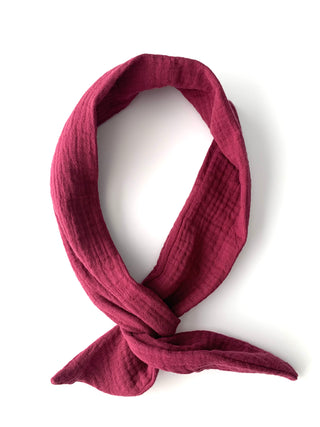 A textured, deep magenta-pink gauze scarf tied in a loop, displayed on a clean white background.