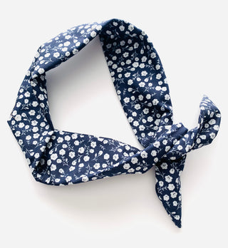A navy blue fabric scarf with a white floral print, styled in a loose knot on a clean white background.