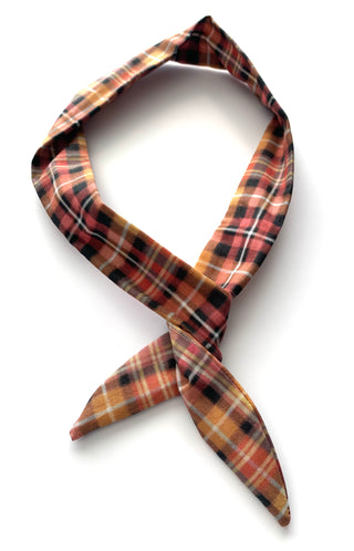A plaid necktie in a warm autumn colorway, featuring orange, red, black, and white stripes, tied in a knot and displayed on a clean white background.