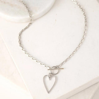 a silver chainlink necklace with a heart pendant 