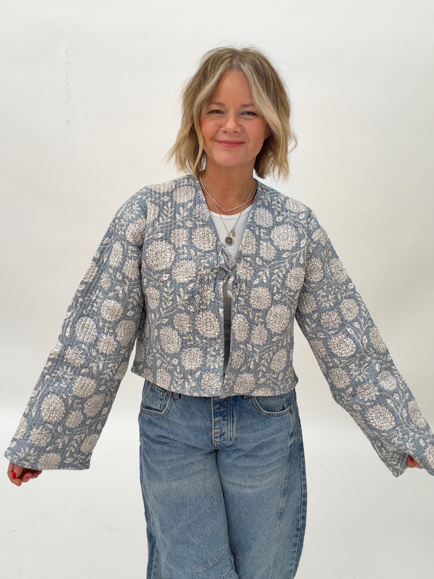 Woman wearing a floral patterned jacket and jeans on a white background