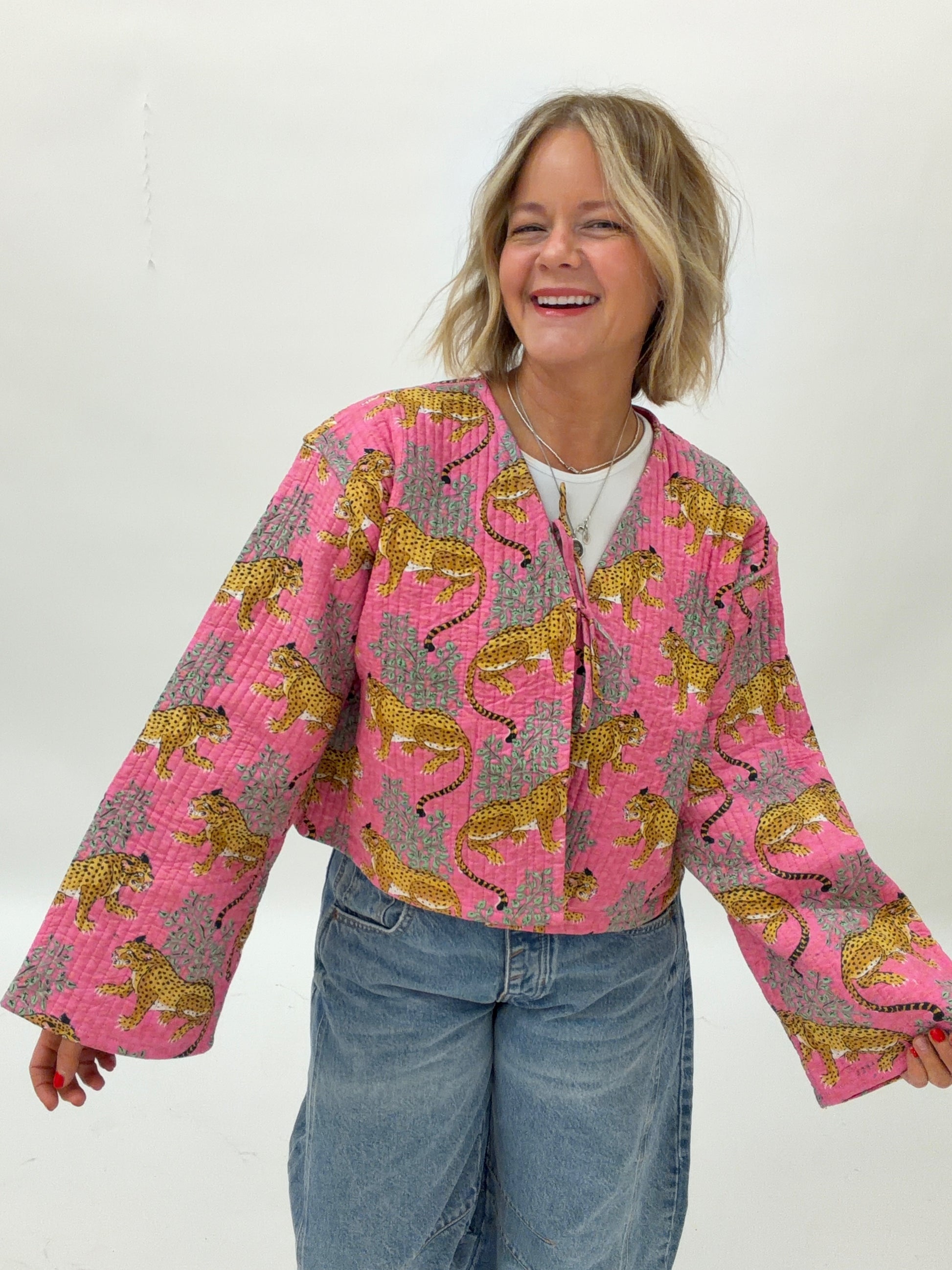 Person wearing a pink quilted jacket with tiger pattern on a white background
