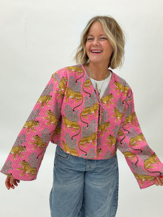 Person wearing a pink quilted jacket with tiger pattern on a white background
