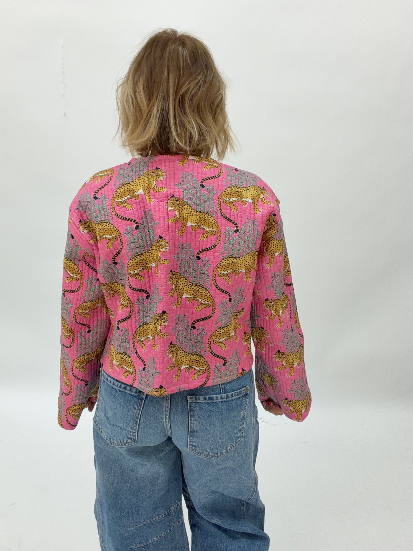 Person wearing a pink patterned shirt with blue jeans on a white background