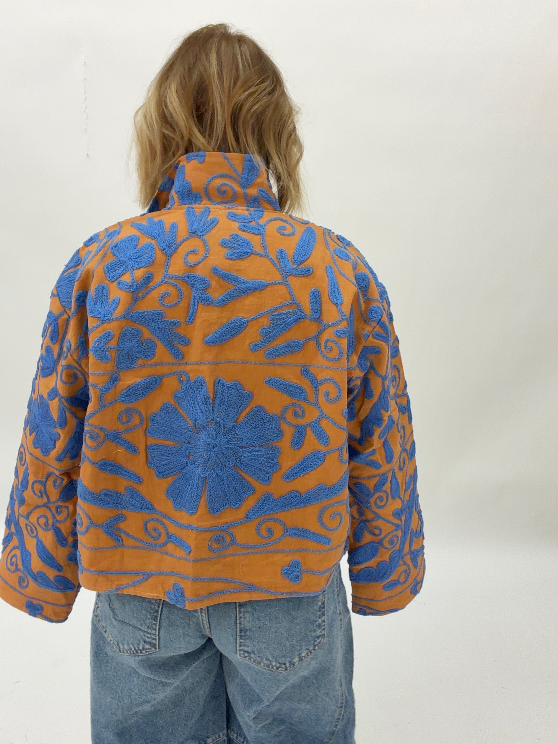 Person wearing a blue and orange patterned jacket on a white background