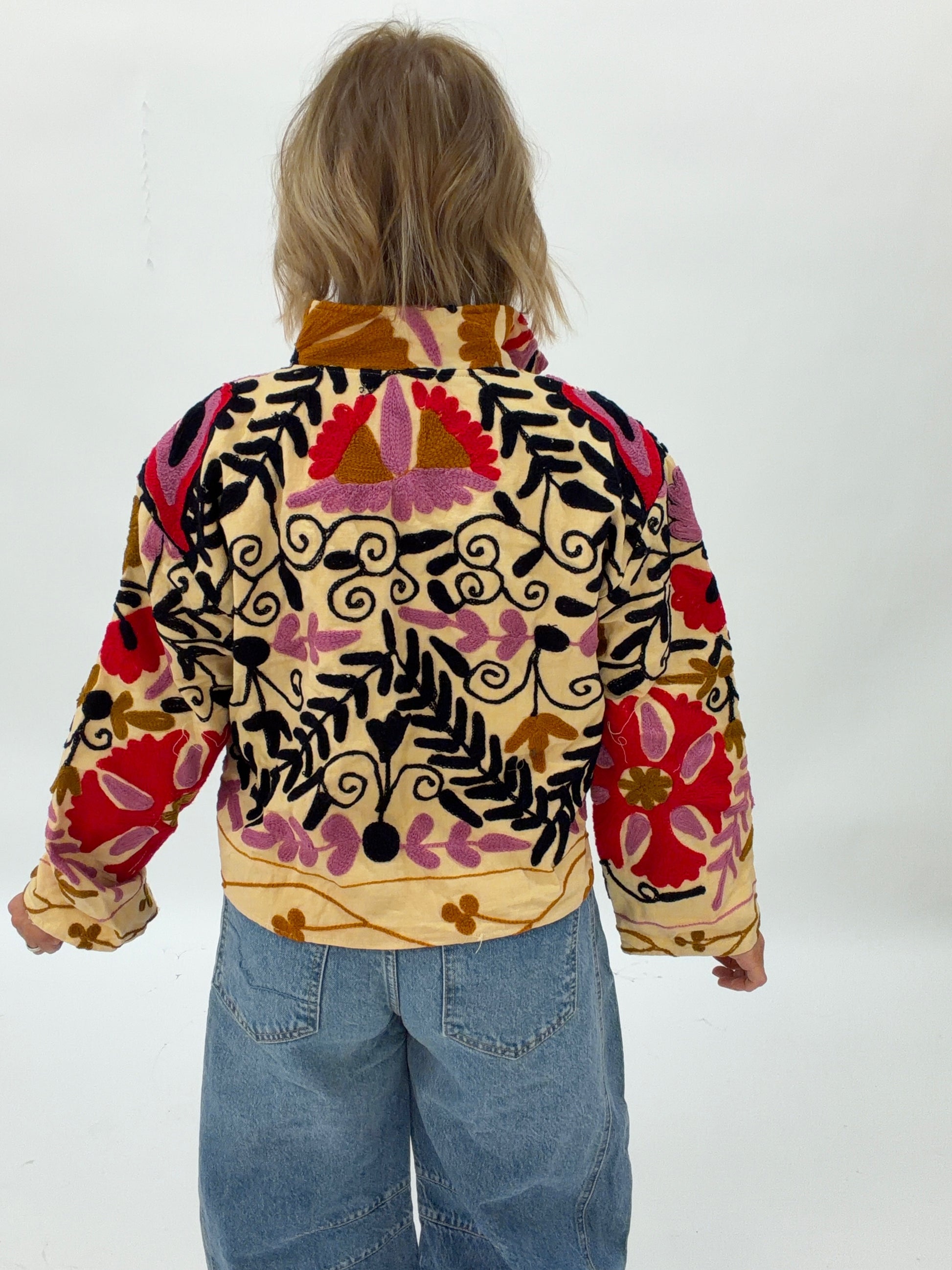 Child wearing a colorful patterned jacket on a white background