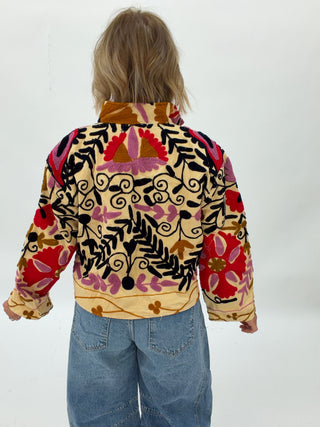 Child wearing a colorful patterned jacket on a white background