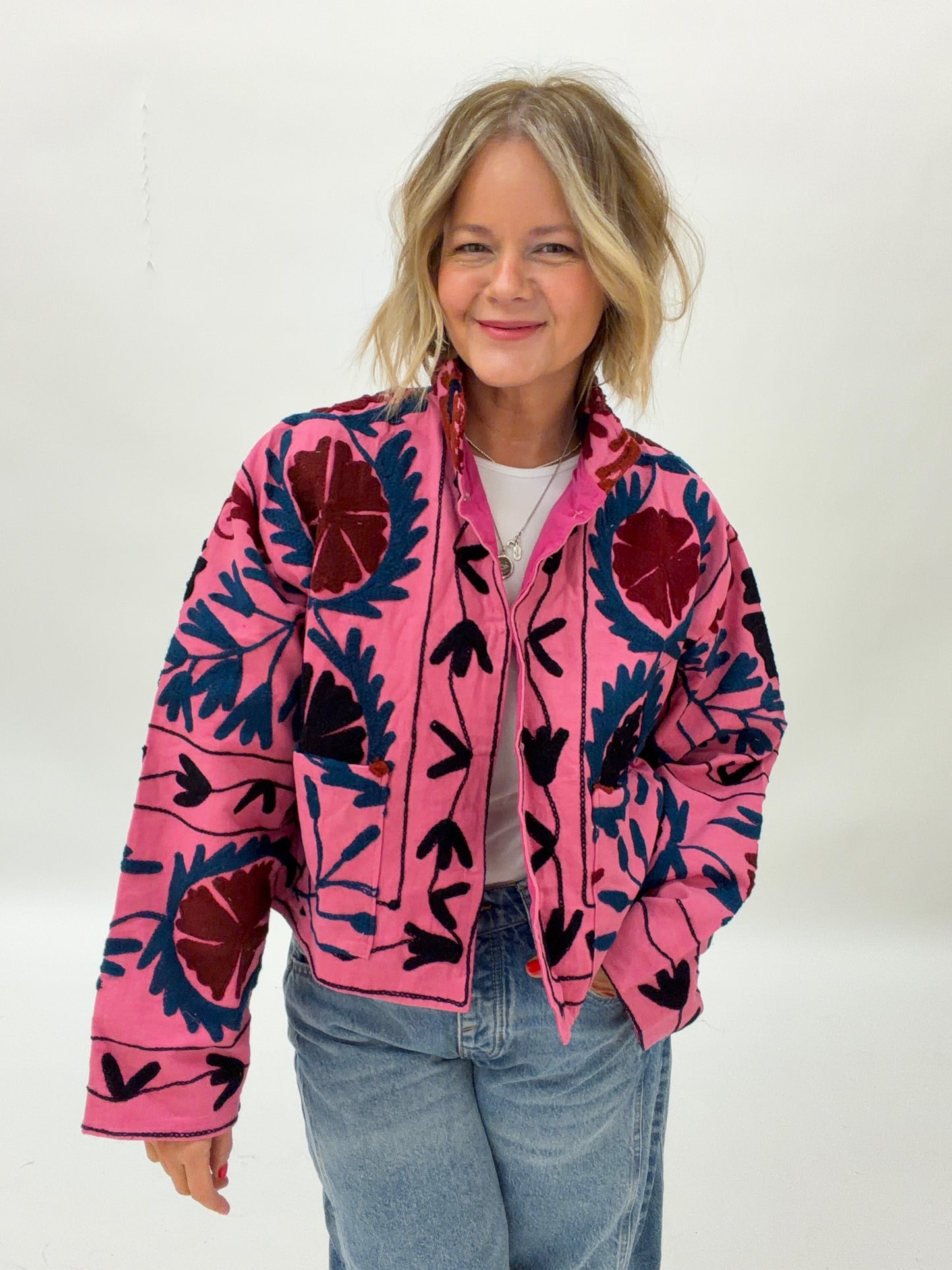 Person wearing a pink jacket with black floral patterns on a white background