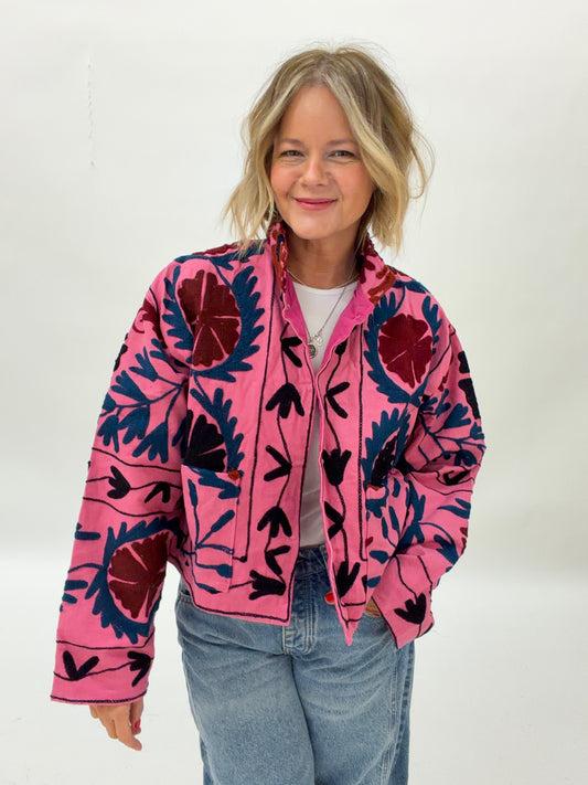 Person wearing a pink jacket with black floral patterns on a white background
