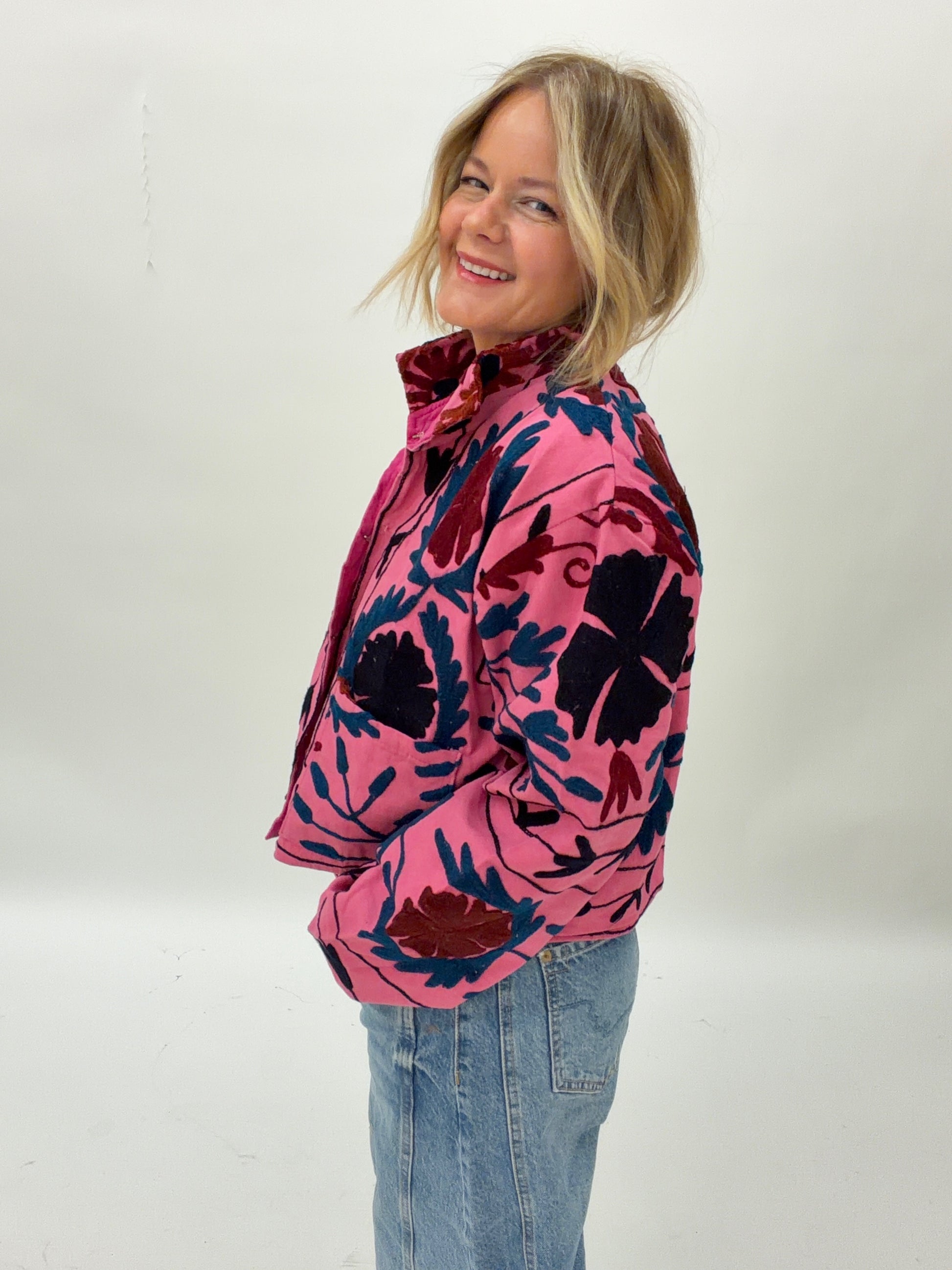 Woman wearing a pink floral jacket with a white background