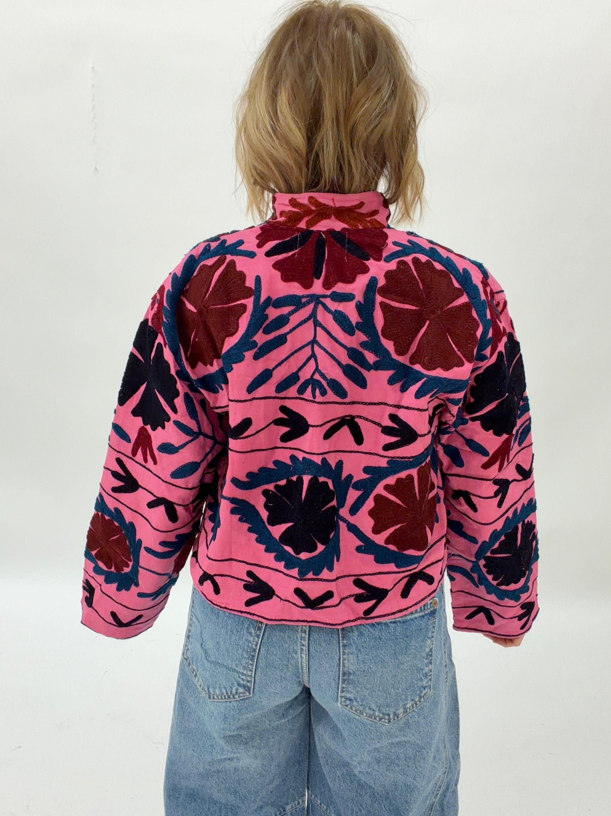 Person wearing a pink and black patterned jacket on a white background