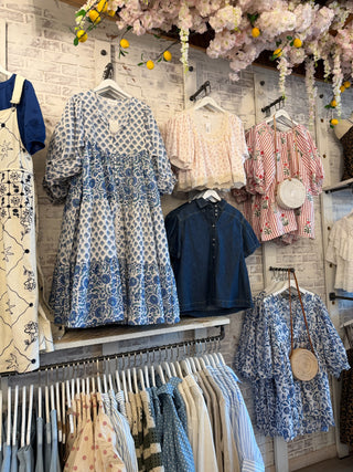 In store display of dresses and blue clothing items.