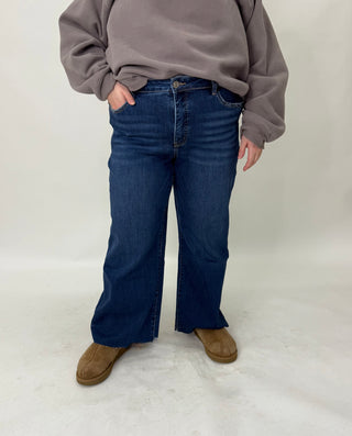Person wearing a gray sweatshirt and blue jeans on a white background