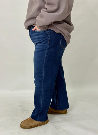 Person wearing blue jeans and a beige sweater on a plain background