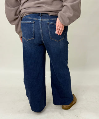 Person wearing blue jeans and a beige sweater on a plain background