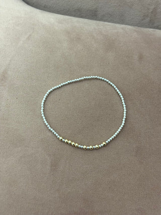 A gold-colored bracelet with small beads, worn on a person's wrist.