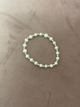 A bracelet featuring white pearls and silver beads displayed on a person's wrist.