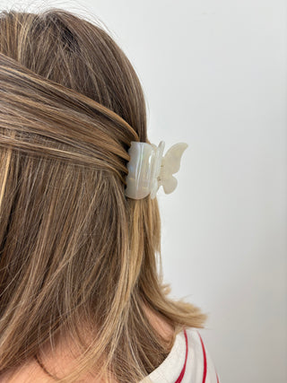 A person with a butterfly-shaped hair clip in multicolor tones attached to their hair.