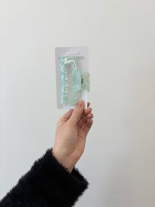 A hand holding a rectangular-shaped hair clip in a translucent green color.