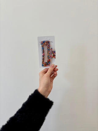 A hand holding a rectangular-shaped hair clip in a translucent green color.