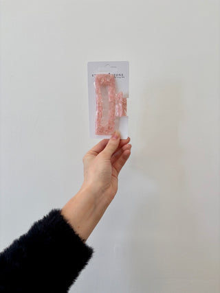 A hand holding a rectangular-shaped hair clip in a translucent green color.