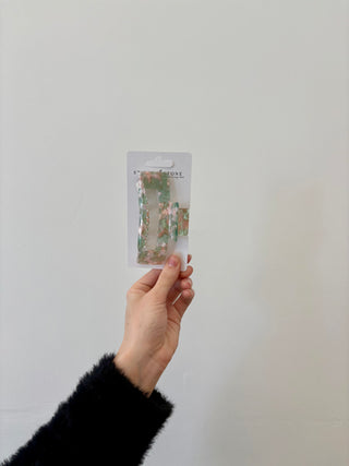 A hand holding a rectangular-shaped hair clip in a translucent green color.