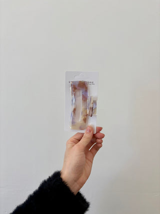 A hand holding a rectangular-shaped hair clip in a translucent green color.